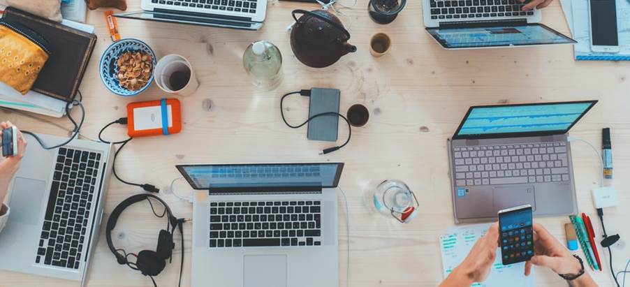 people sitting down near table with assorted laptop computers
